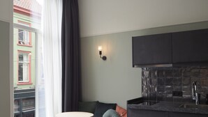Une cuisine compacte avec des meubles sombres et un pare-feu en carreaux, une petite table ronde et un banc avec des coussins.