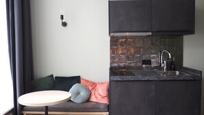 Une cuisine de taille réduite, avec des meubles de couleur sombre, un pare-feu en carrelage et un évier encastré.