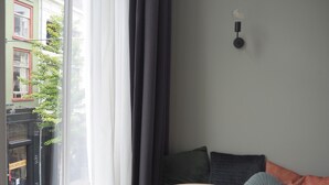 Une pièce d’angle avec une fenêtre, une table ronde et un canapé avec des coussins.
