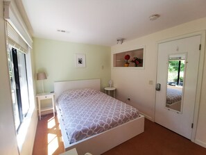 A bedroom with a bed, bedside table, lamp, and a mirror. - POWER ON - The Forest Rooms -- A Peaceful Oasis close to everything (Issaquah)