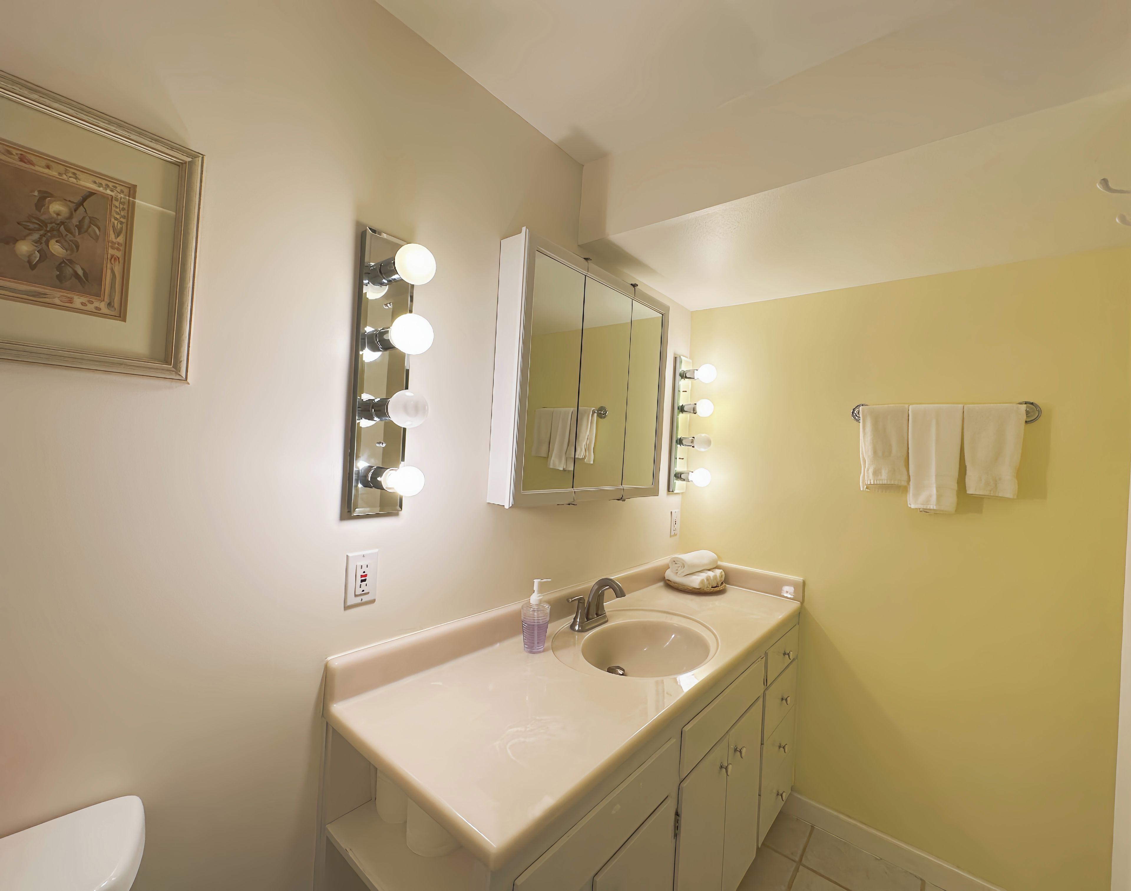 Une salle de bain équipée d’un meuble-lavabo, d’un miroir et d’un porte-serviettes.