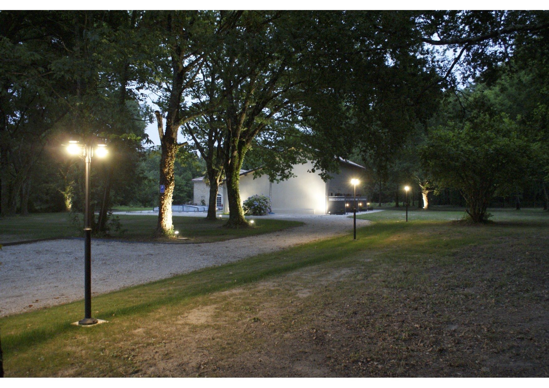 A pathway leading to a building with a gravel area and trees.