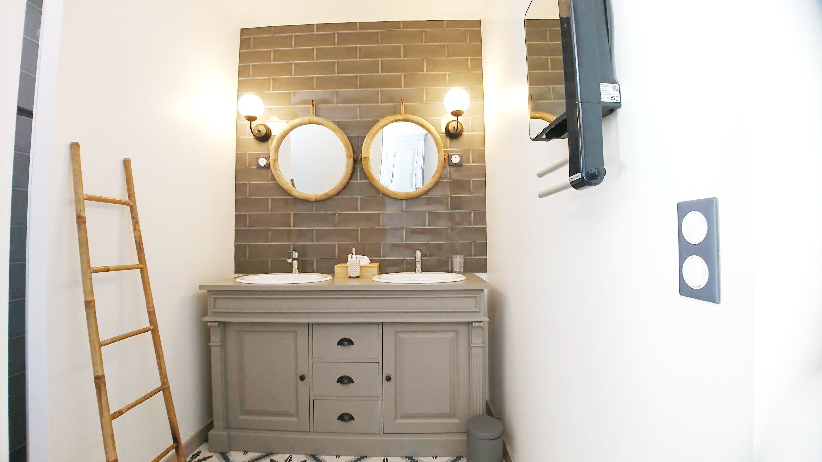 Une salle de bain avec deux lavabos, un miroir et un porte-serviettes.