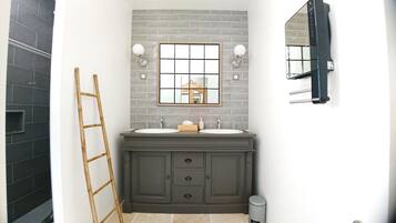 A bathroom with a double sink vanity, a mirror, and a towel rack.