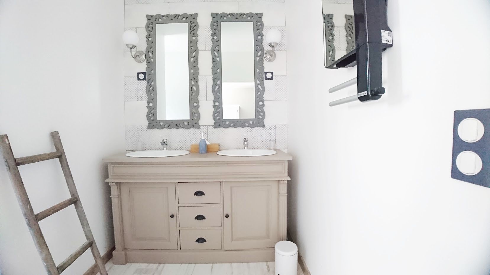 Une salle de bain avec deux lavabos, un meuble-lavabo avec des tiroirs, un porte-serviettes échelle et des toilettes.
