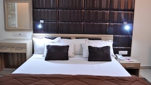 A hotel room with a large bed, a wooden headboard, bedside tables, a mirror, and a wall-mounted light fixture. - Hotel Solo Victoria (New Delhi)