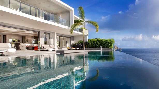 Une maison moderne dotée d’une piscine, de mobilier d’extérieur et offrant une vue sur l’océan.