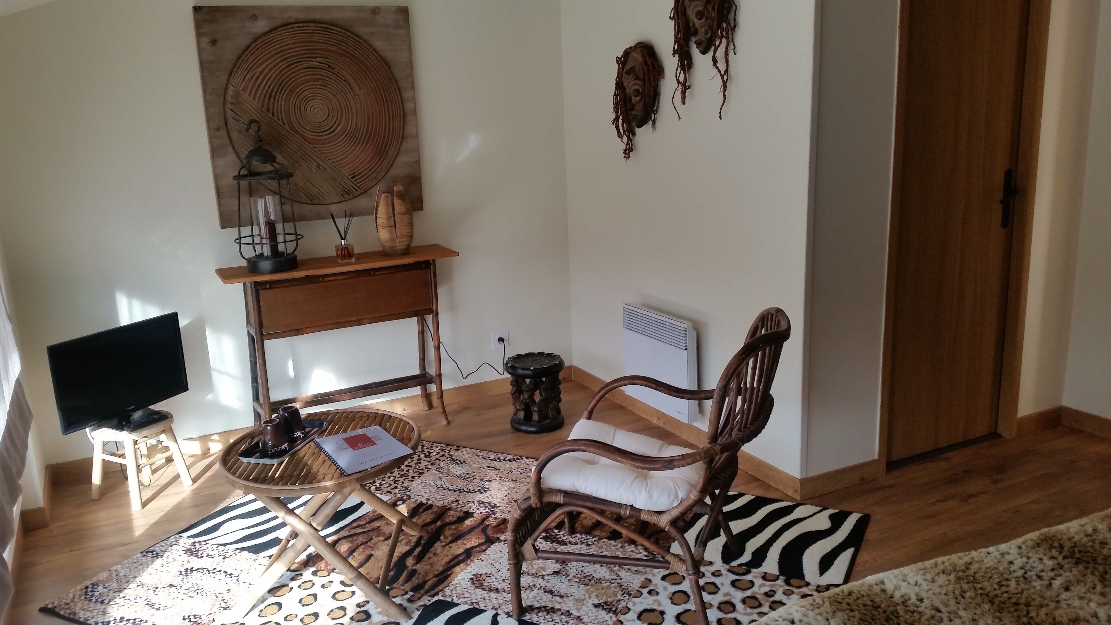 A living room with a television, a wooden table with a lamp, a chair, and a patterned rug.