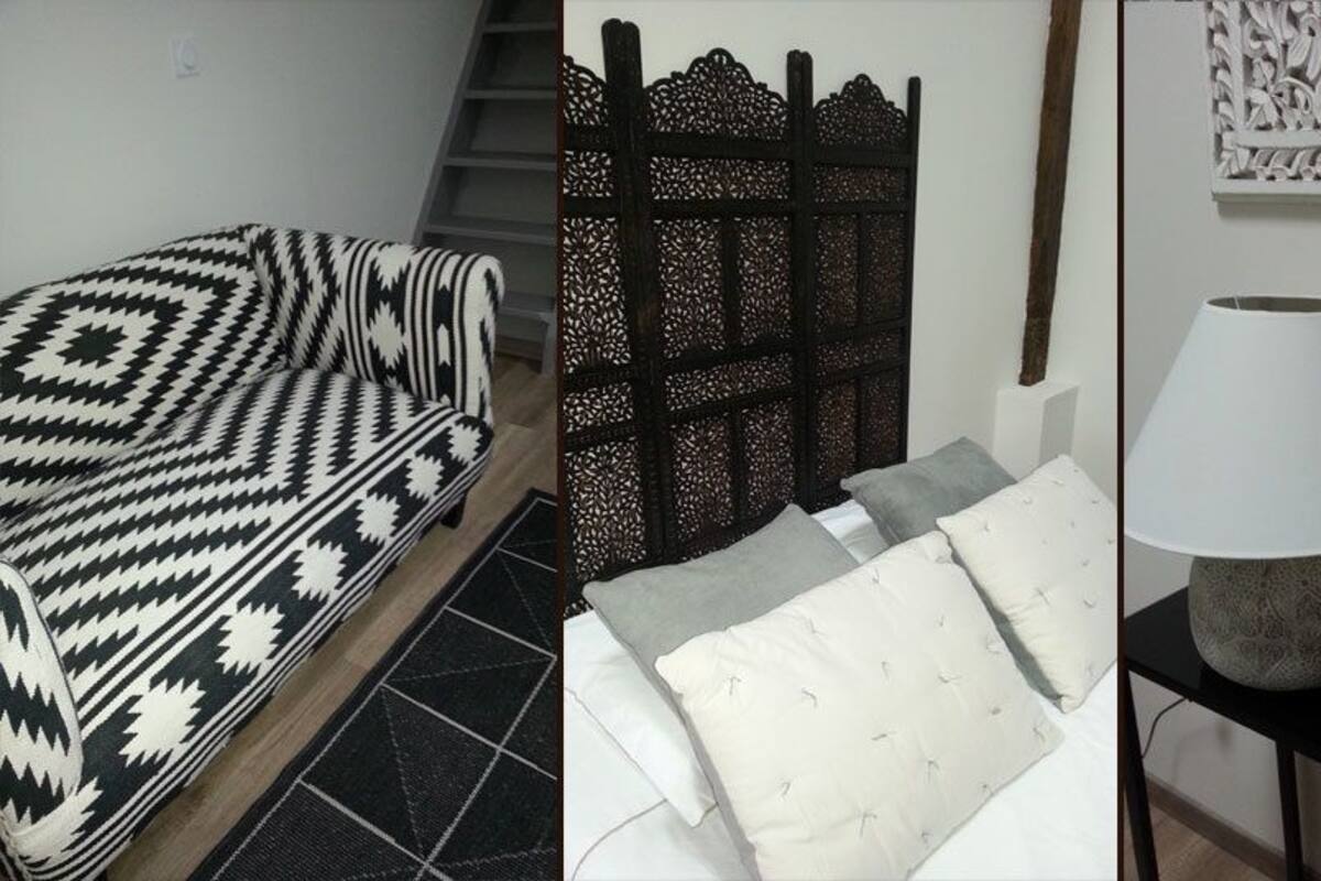 A bed with a patterned blanket, a headboard with intricate designs, a bedside table with a lamp, and decorative wall art.