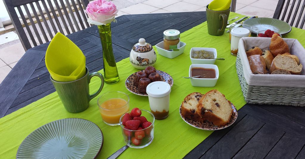 Une table dressée avec des aliments pour le petit-déjeuner, notamment des viennoiseries, des fruits et des boissons.