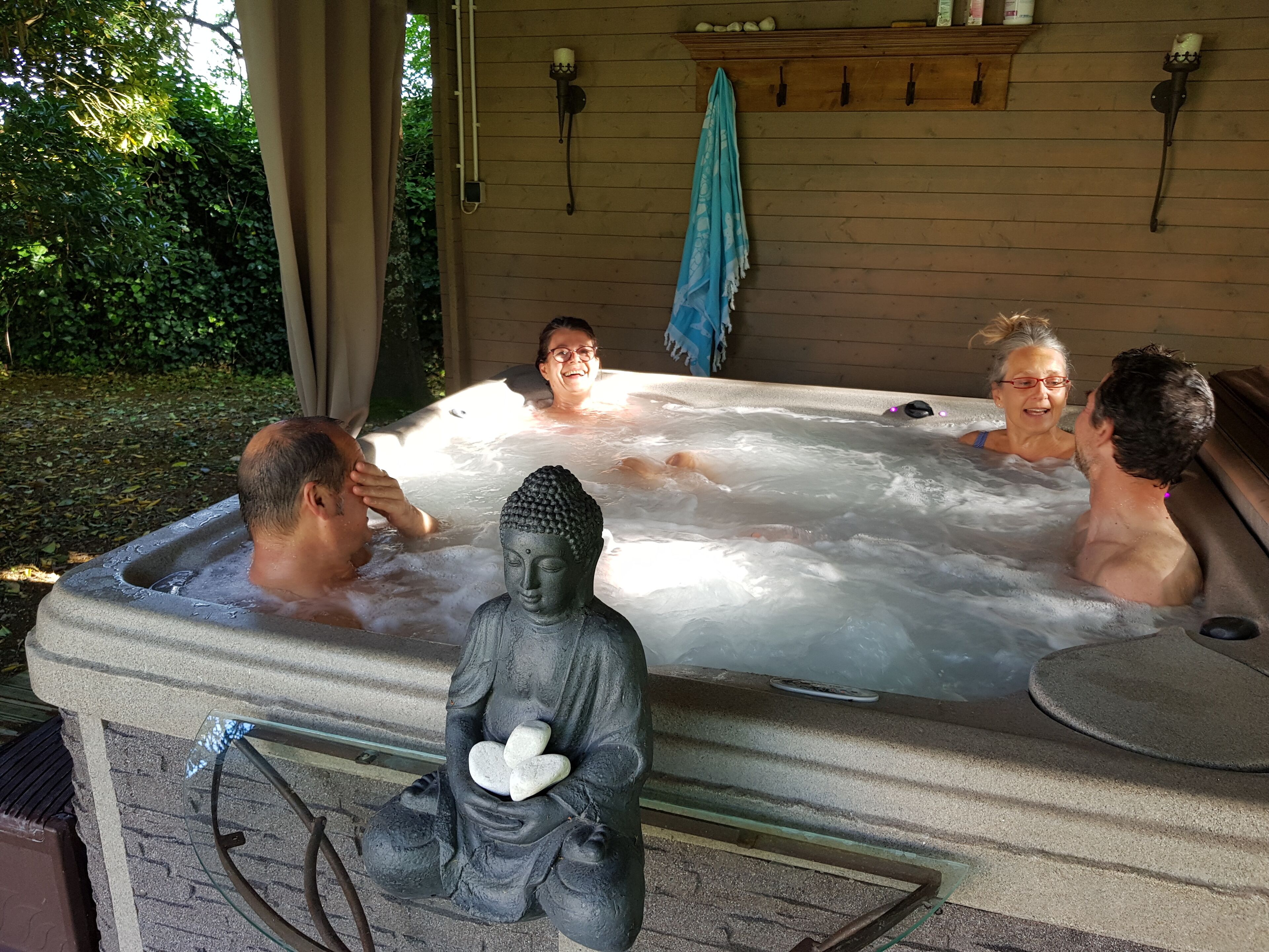 A hot tub with a Buddha statue in the center, surrounded by people.