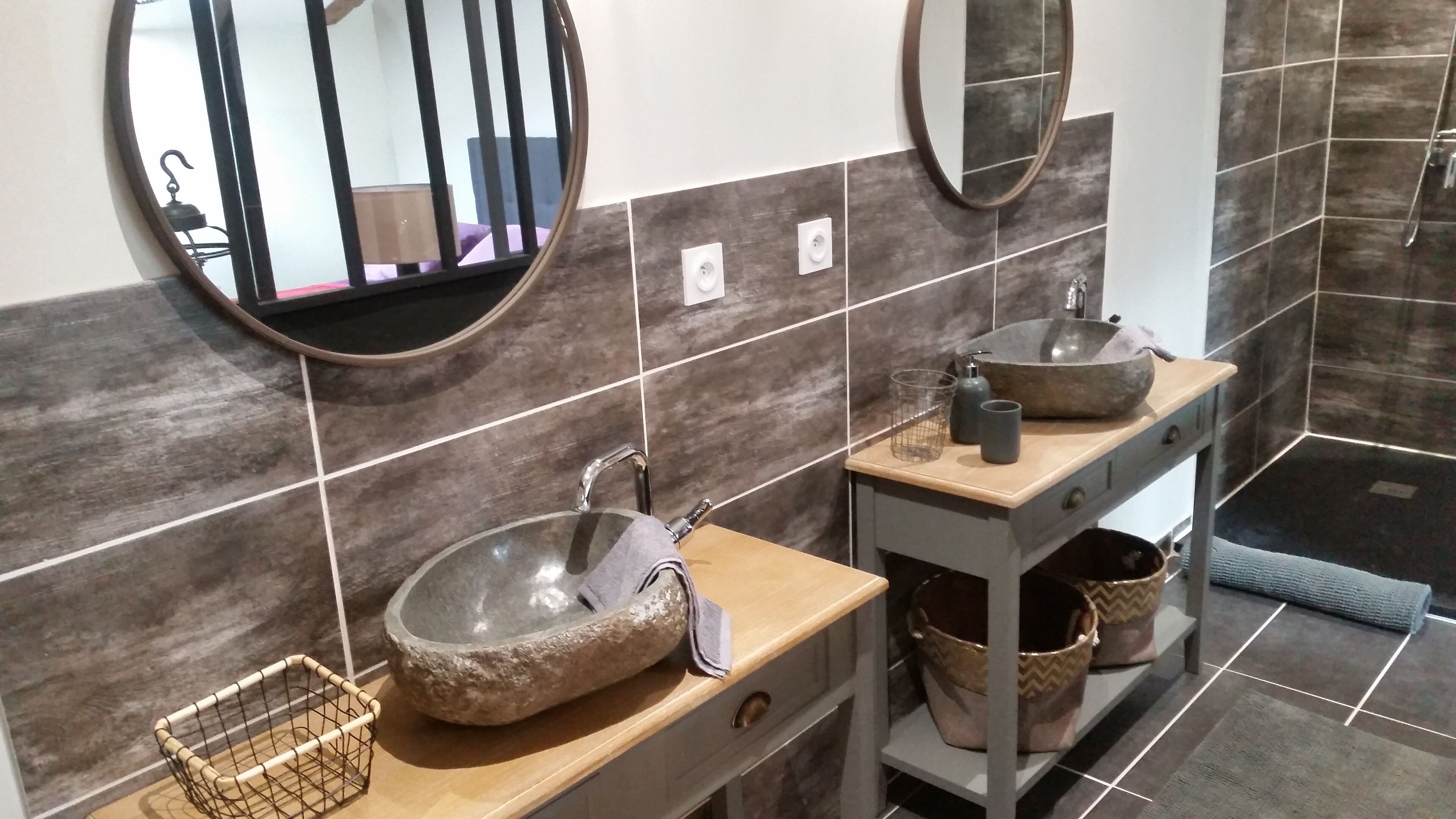 Un baño moderno con un lavabo de piedra, dos espejos, un perchero y una zona de ducha.