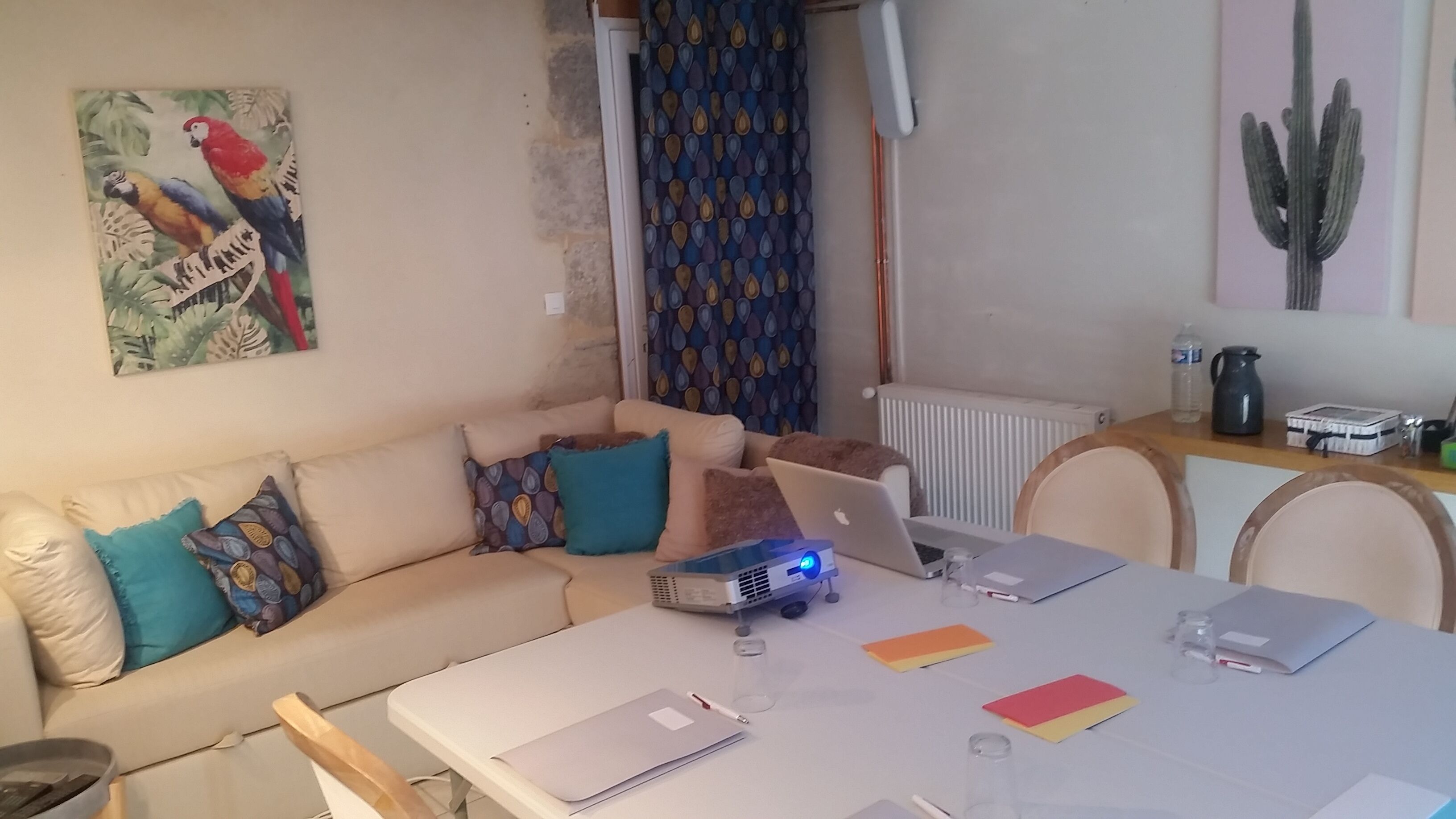 A living room with a sofa, a coffee table, a laptop, and a projector.