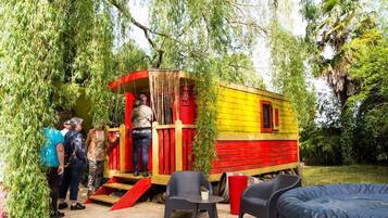 Une petite construction en bois aux couleurs vives, avec une façade rouge et jaune, entourée de verdure.