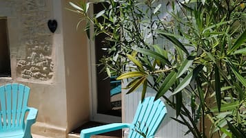 A patio area with two turquoise Adirondack chairs, a potted plant, and a stone wall.