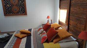 Un dormitorio con cama, almohadas, una lámpara y una obra de arte en la pared.
