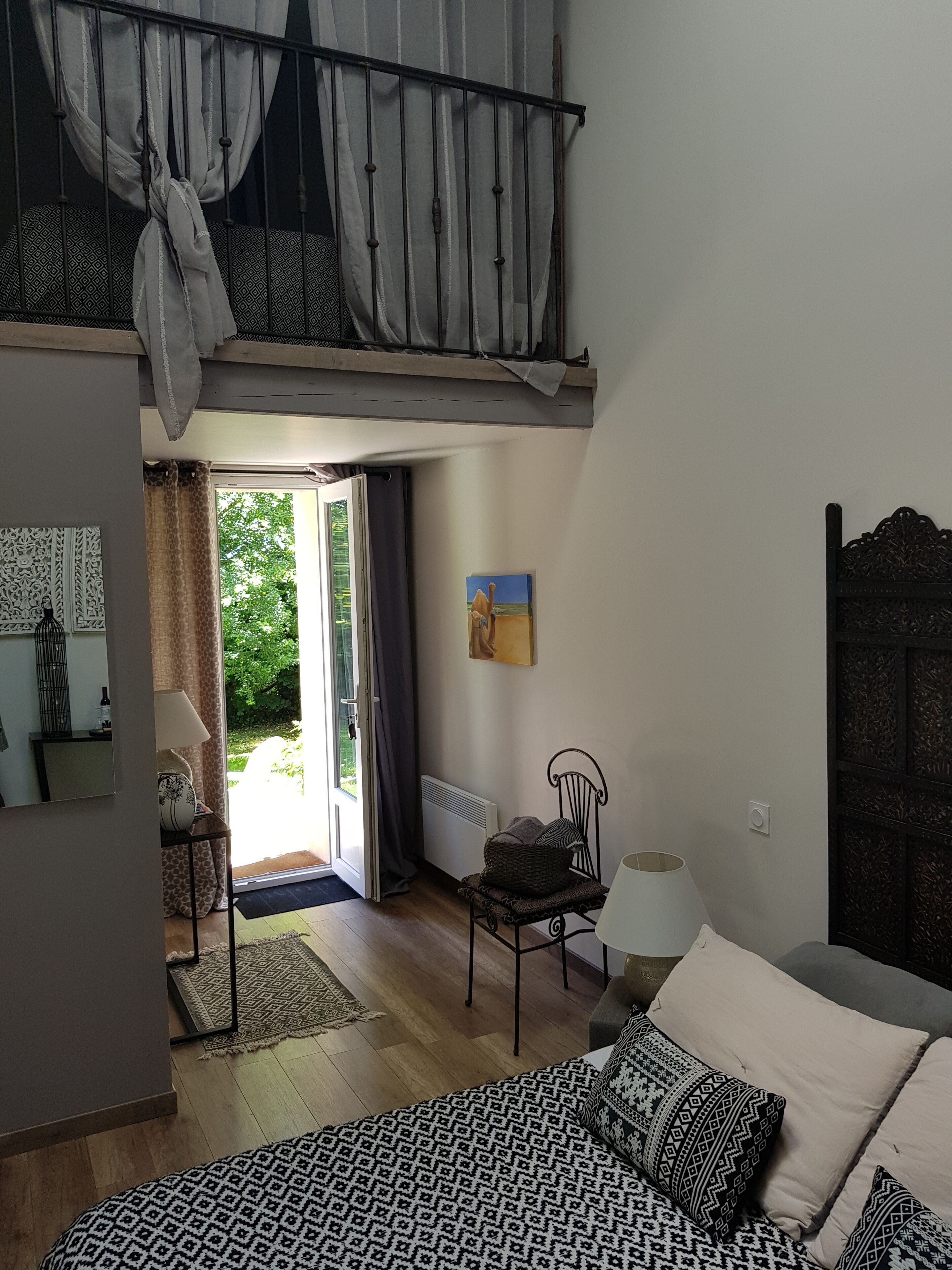 Un dormitorio con cama, una silla, un radiador y un cuadro en la pared.