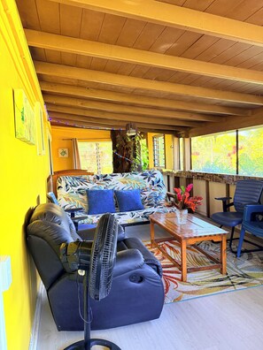 Un espace extérieur aménagé, abrité et doté d’un canapé, de chaises, d’un ventilateur et d’une table.