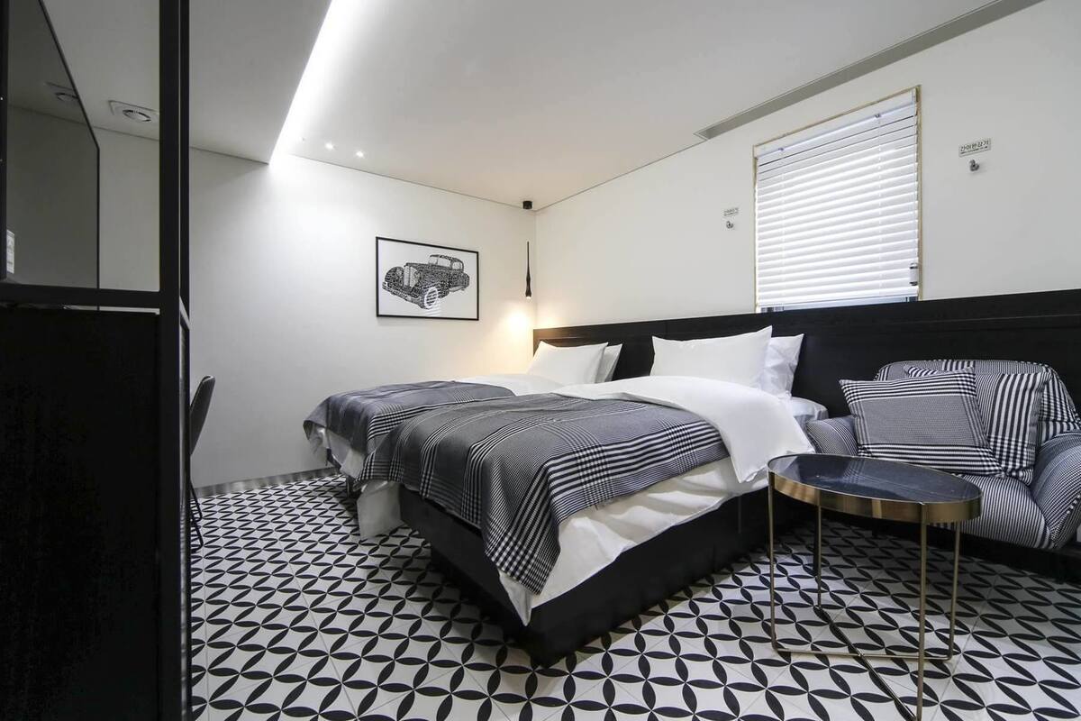A hotel room with a bed, bedside table, chair, and a patterned floor.