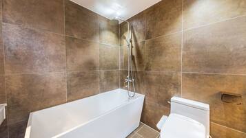 Een moderne badkamer met een bad, douche en toilet.