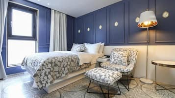 A bedroom with a bed, a chair, a lamp, and a window.