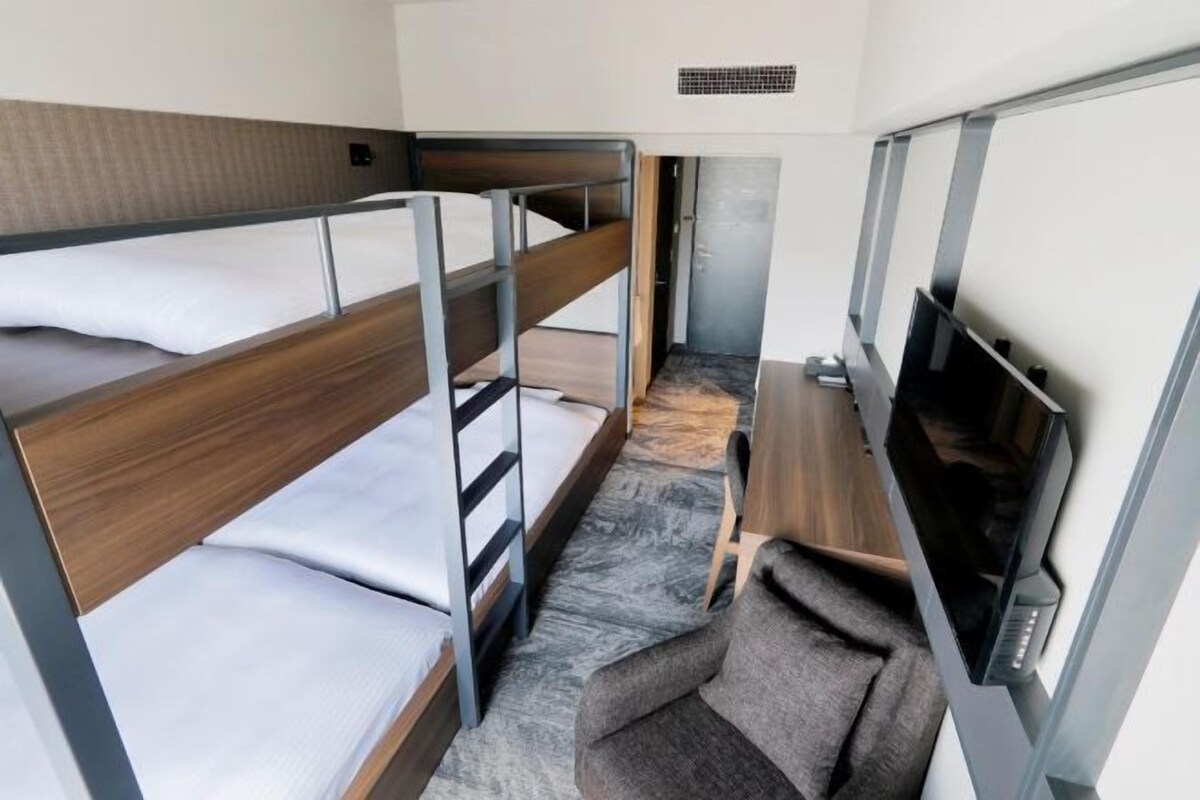 Habitación con literas, televisor y una pequeña zona de estar.