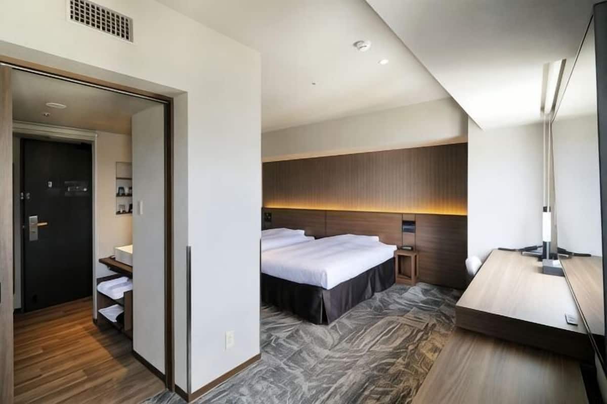 Quarto de hotel com cama, mesa de cabeceira e espelho.
