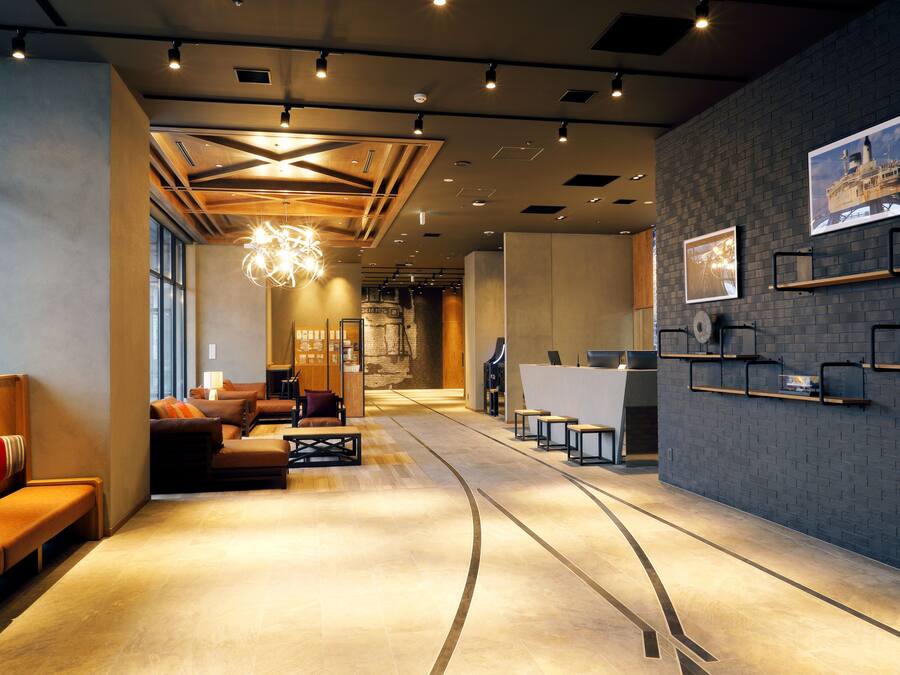 A modern hotel lobby with a reception desk, seating area, and artwork on the walls.