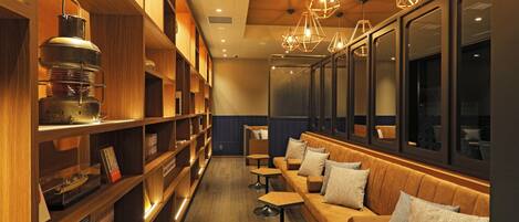 A cozy seating area with wooden shelves and tables, a sofa with cushions, and geometric pendant lights.