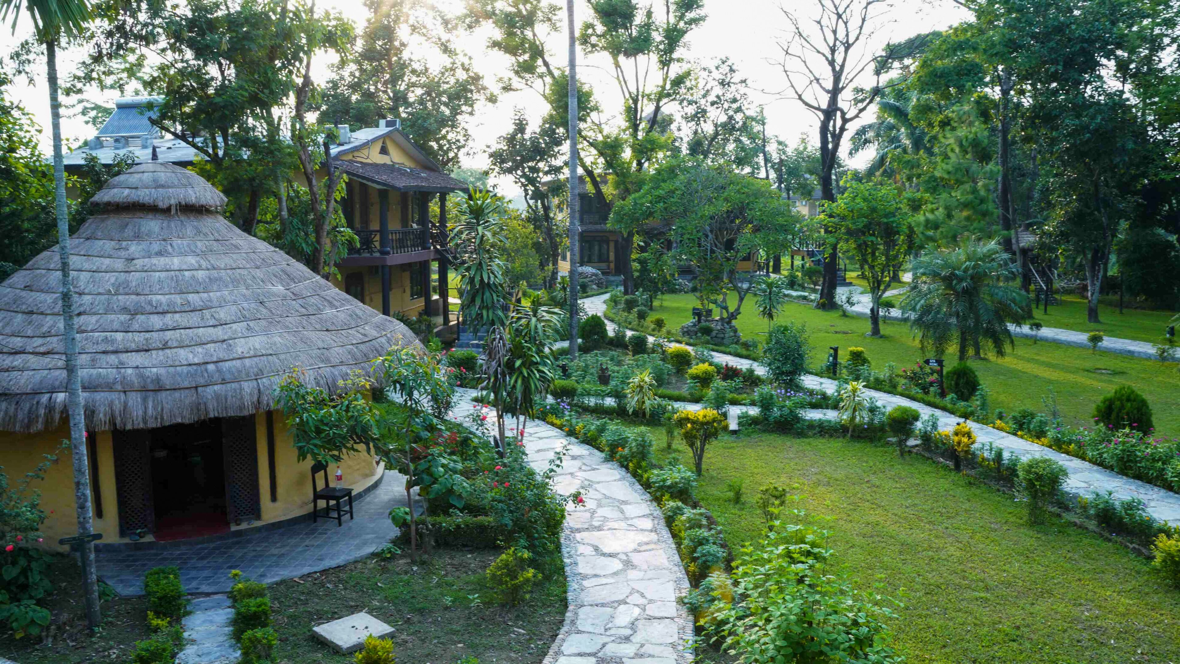 A traditional thatched-roof structure with a stone pathway leading to a well-maintained garden.