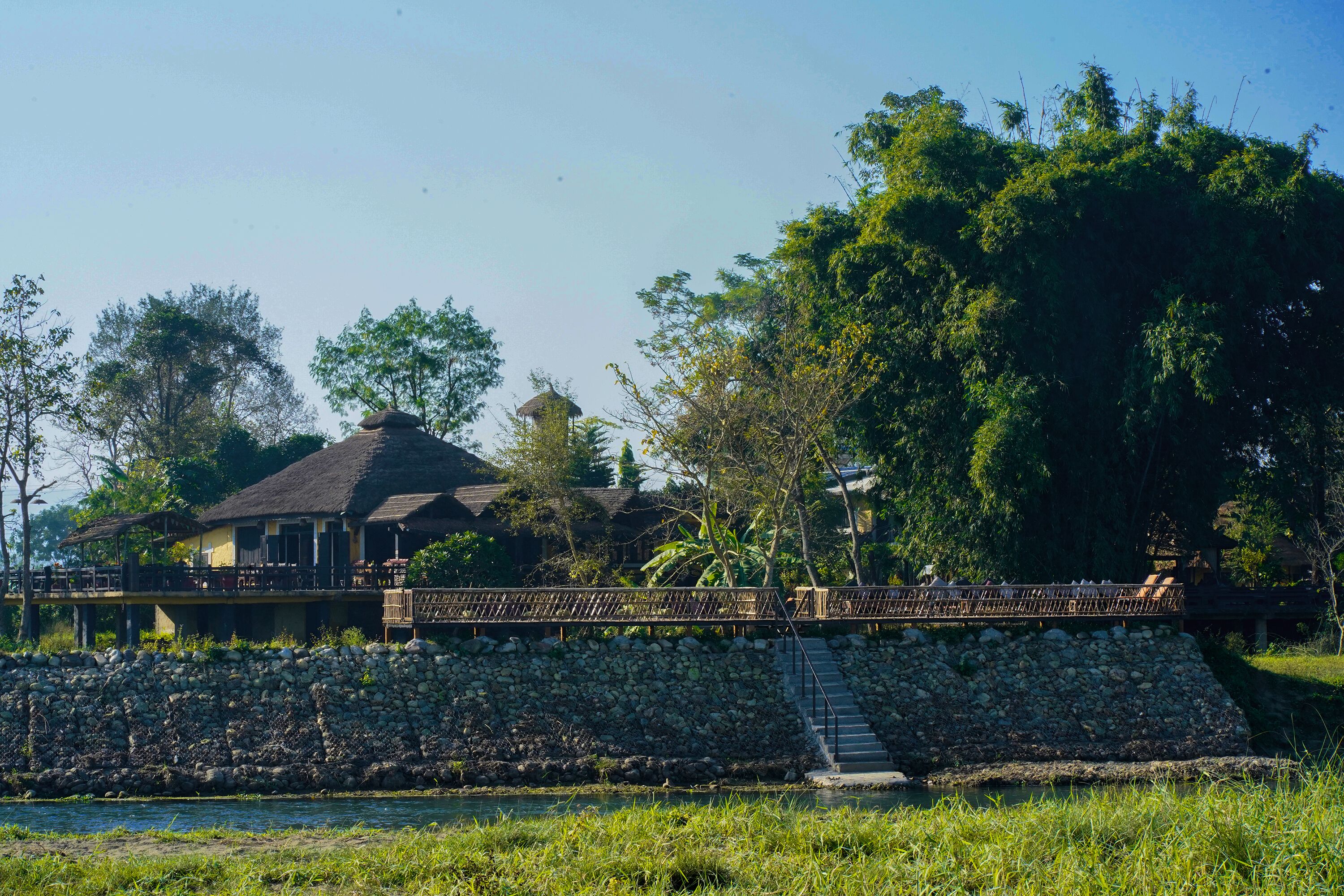 A stone wall with a staircase leading to a wooden bridge over a body of water.