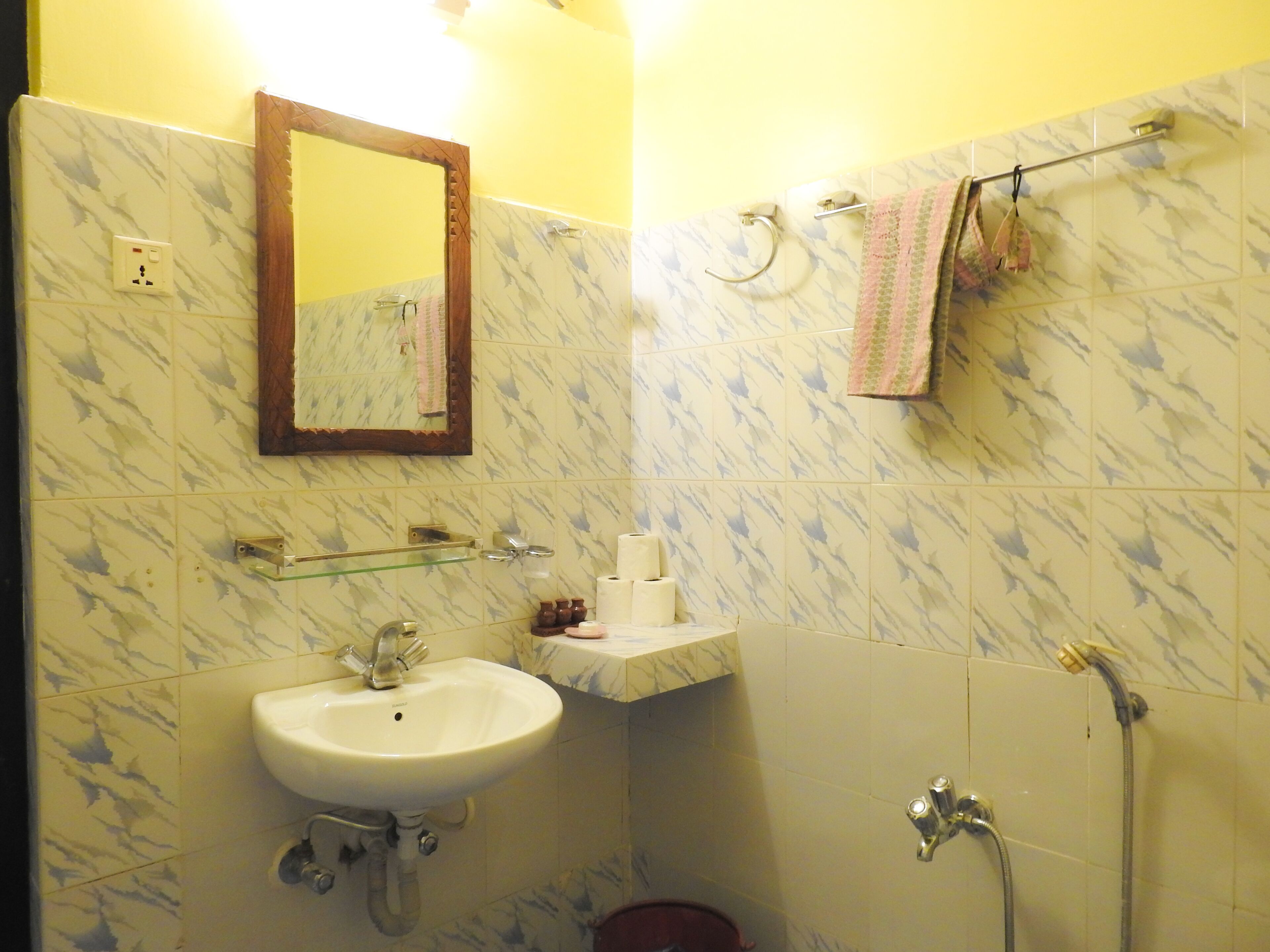 A bathroom with a sink, mirror, towel rack, and shower.