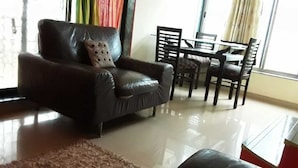 A living room with a leather armchair, a dining table with chairs, and a rug.