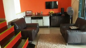 A living room with a sofa, a coffee table, and a TV mounted on the wall.