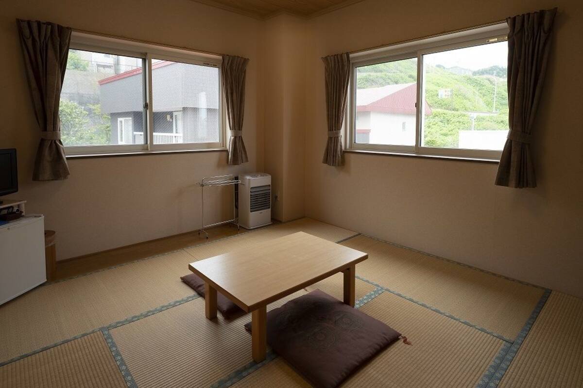 A room with tatami flooring, a low table, a cushion, and a heater.