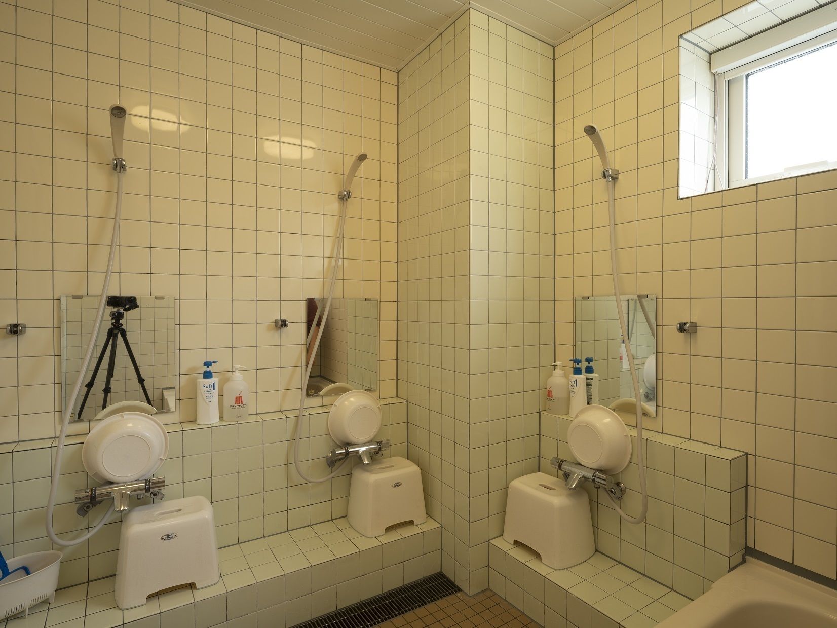A bathroom with three toilets, a bidet, a hand dryer, and a mirror.