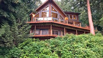 A multi-level wooden cabin with balconies, surrounded by dense forest.