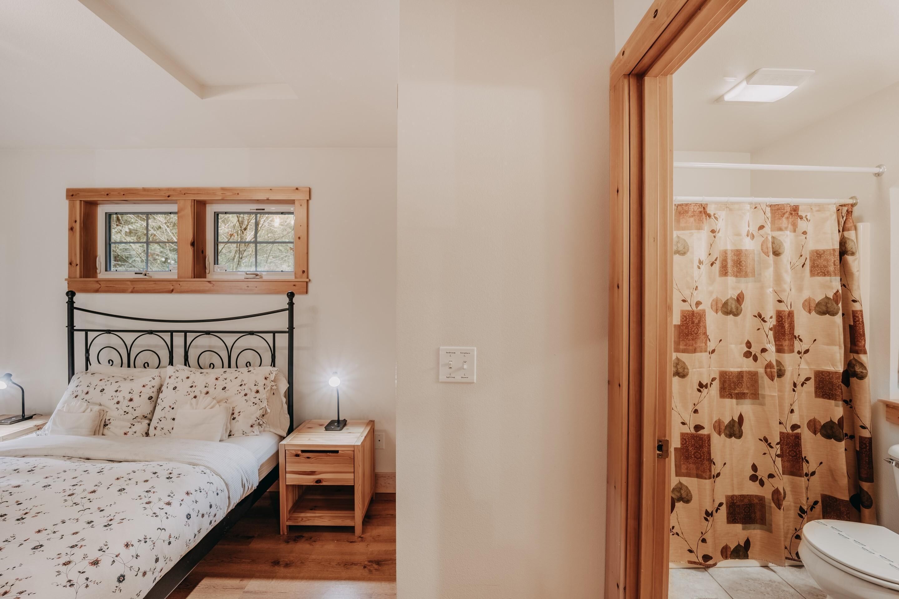 A bedroom with a bed, nightstand, and a window above the bed.