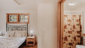 A bedroom with a bed, nightstand, and a window above the bed.