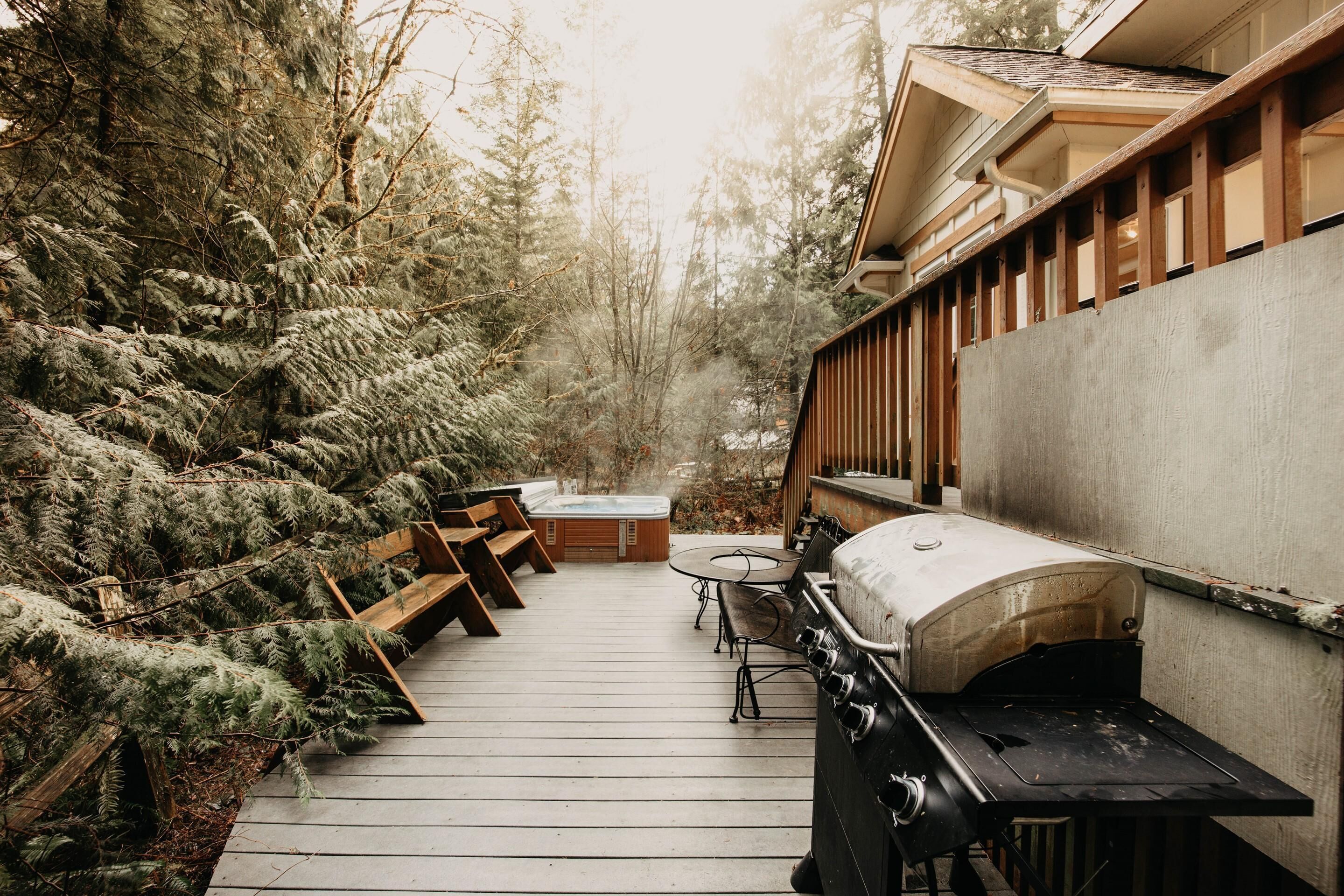 A wooden deck with a hot tub, barbecue grill, and outdoor seating.