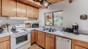 A modern kitchen with wooden cabinets, a stove, a dishwasher, and a coffee maker. - 67MF- Hot Tub - Pets Ok - BBQ - Sleeps 5 (Maple Falls)