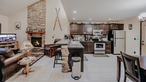 A modern living room with a stone fireplace, a kitchen with dark wooden cabinets, and a dining area. - 89GS - Hot Tub - Pets Ok - WiFi - Sleeps 4 (Deming)