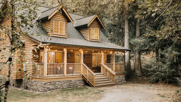 A log cabin with a porch, stone foundation, and a dirt path leading to the entrance. - 89GS - Hot Tub - Pets Ok - WiFi - Sleeps 4 (Deming)