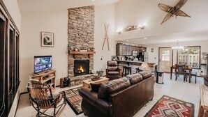 A spacious living area with a stone fireplace, leather sofa, and a television. - 89GS - Hot Tub - Pets Ok - WiFi - Sleeps 4 (Deming)