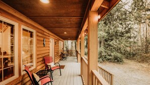 A wooden cabin with a porch, two chairs, and a table. - 89GS - Hot Tub - Pets Ok - WiFi - Sleeps 4 (Deming)