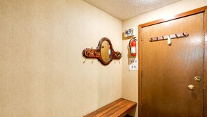 A wooden bench, a wooden door, a wall-mounted mirror, and a fire extinguisher.