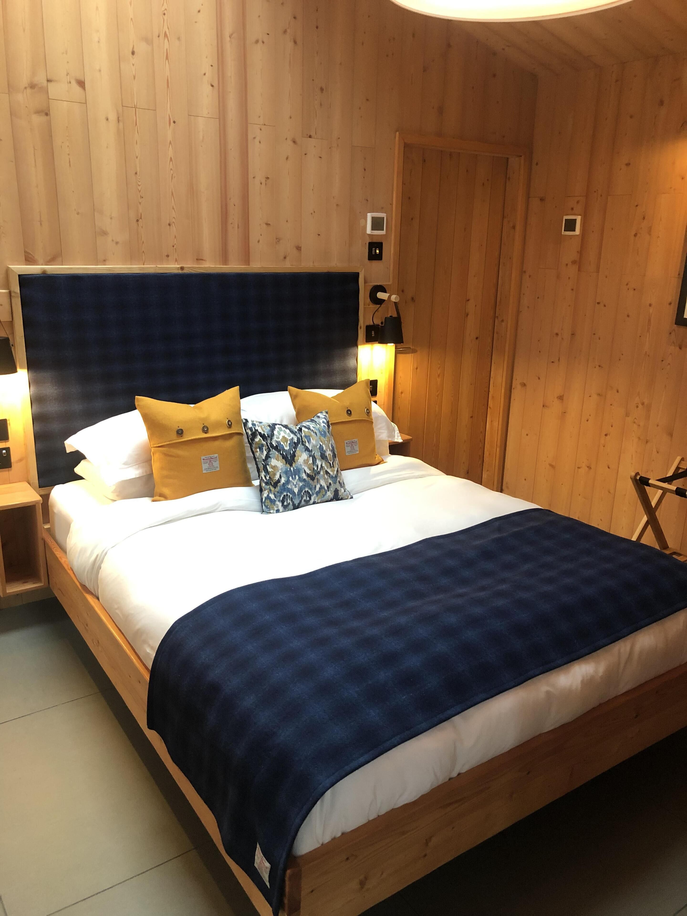 A wooden-paneled room with a bed, a nightstand, and a lamp.