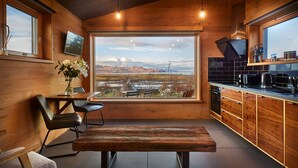 A modern kitchen with a large window, wooden cabinetry, and a bench in the center. - Ardcana (Strath)