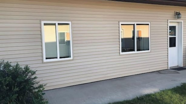 Un edificio a un piano con rivestimento beige, due finestre e una porta.