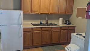 Una cucina compatta con mobili in legno, un frigorifero, un lavello e un piano cottura.